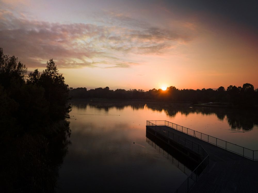The Sun is Setting Over a Lake With a Dock in the Foreground — CBS Chainsaw & Brushcutter Specialists - HUSQVARNA in Harrington, NSW