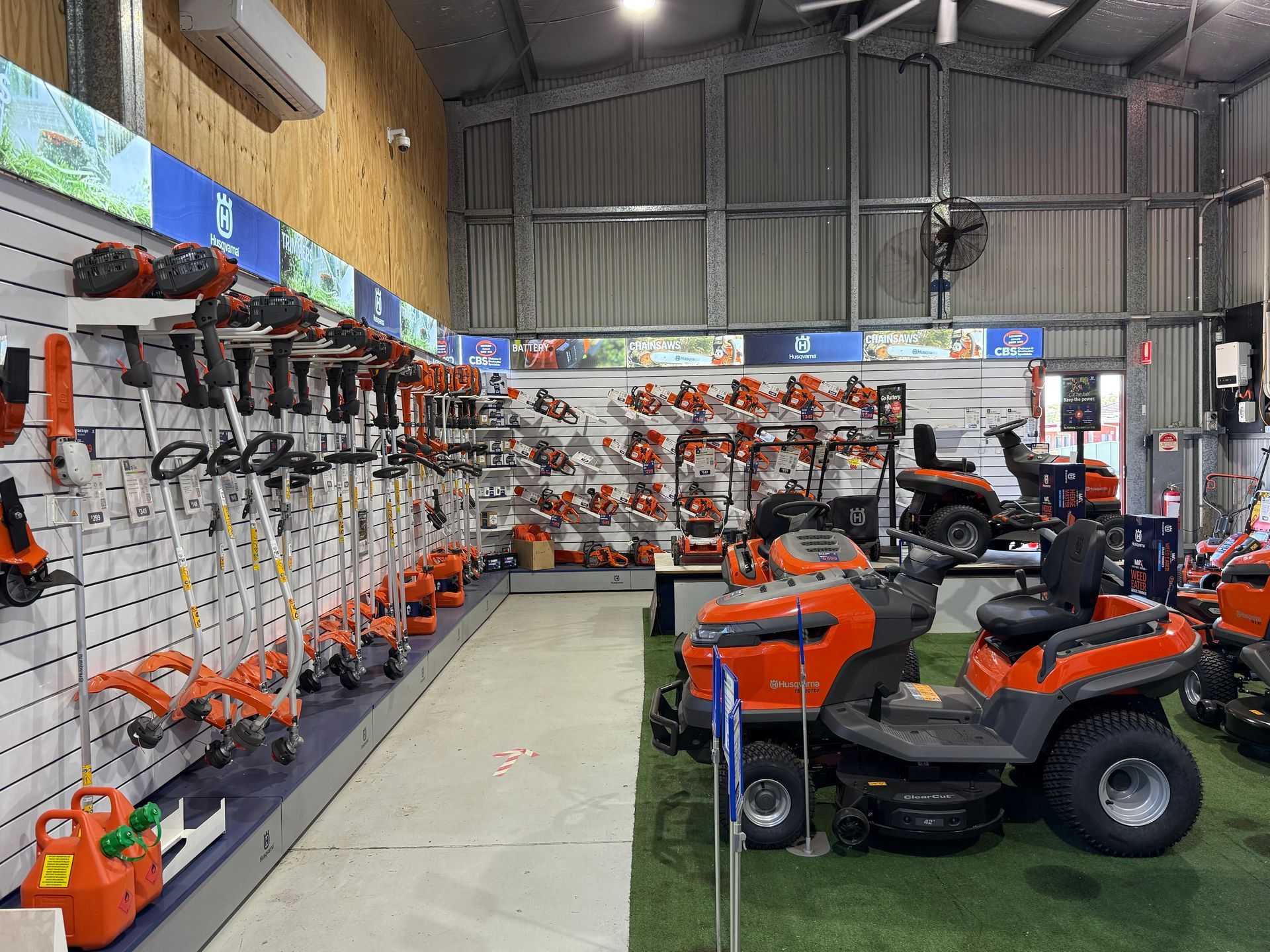 Husqvarna power tool display in a store. Blowers and robotic lawn mowers in orange and black. — CBS Chainsaw & Brushcutter Specialists - HUSQVARNA in Wauchope, NSW