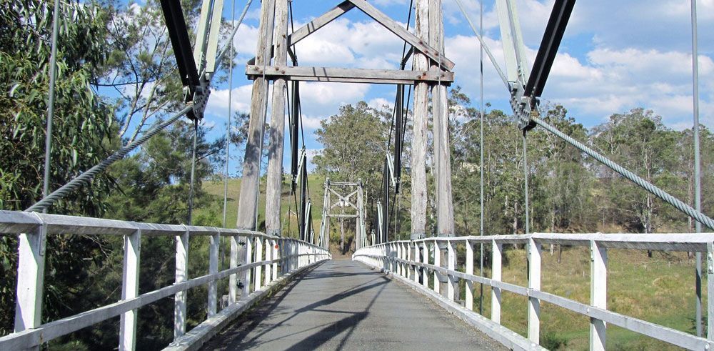 A Suspension Bridge Over a River With Trees in the Background — CBS Chainsaw & Brushcutter Specialists - HUSQVARNA in Wauchope, NSW