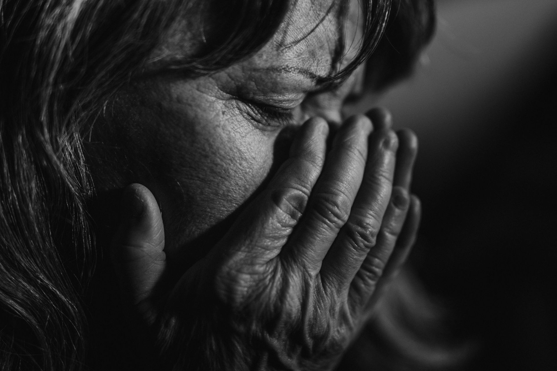 Close-up of grieving elderly woman, black and white photo.