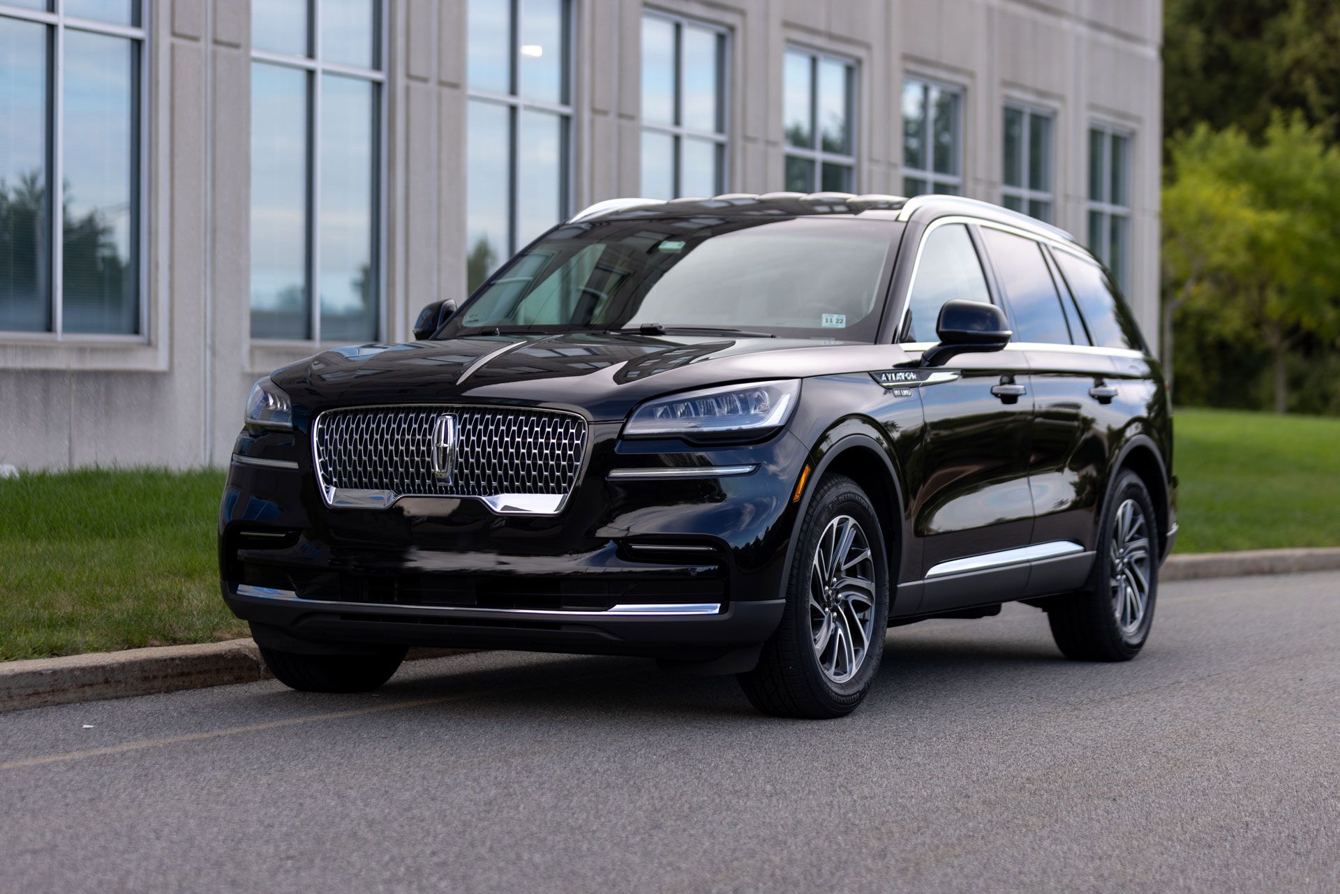 A black lincoln aviator is parked on the side of the road in front of a building.