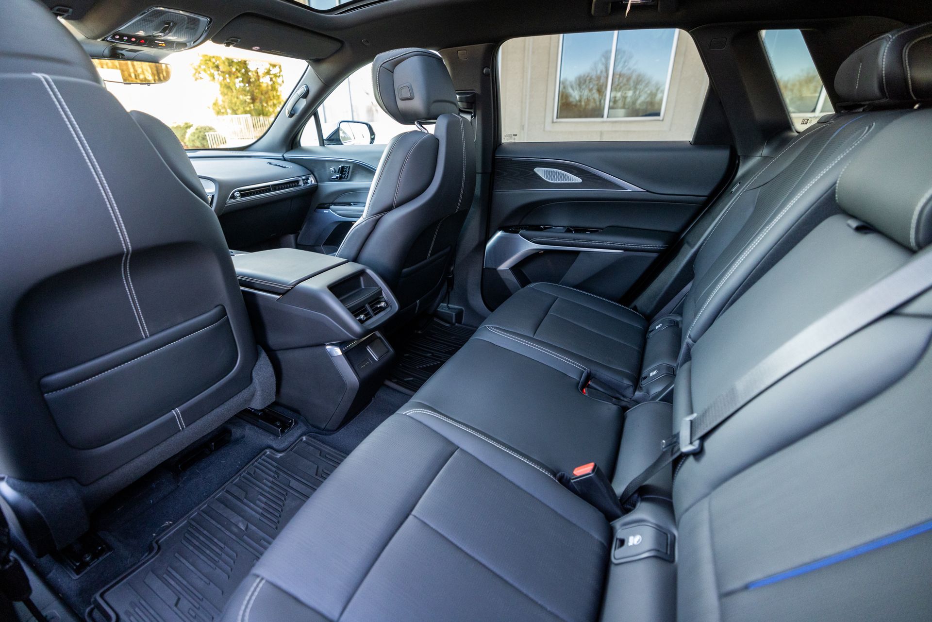 The rear seats of a car are empty and have seat belts.