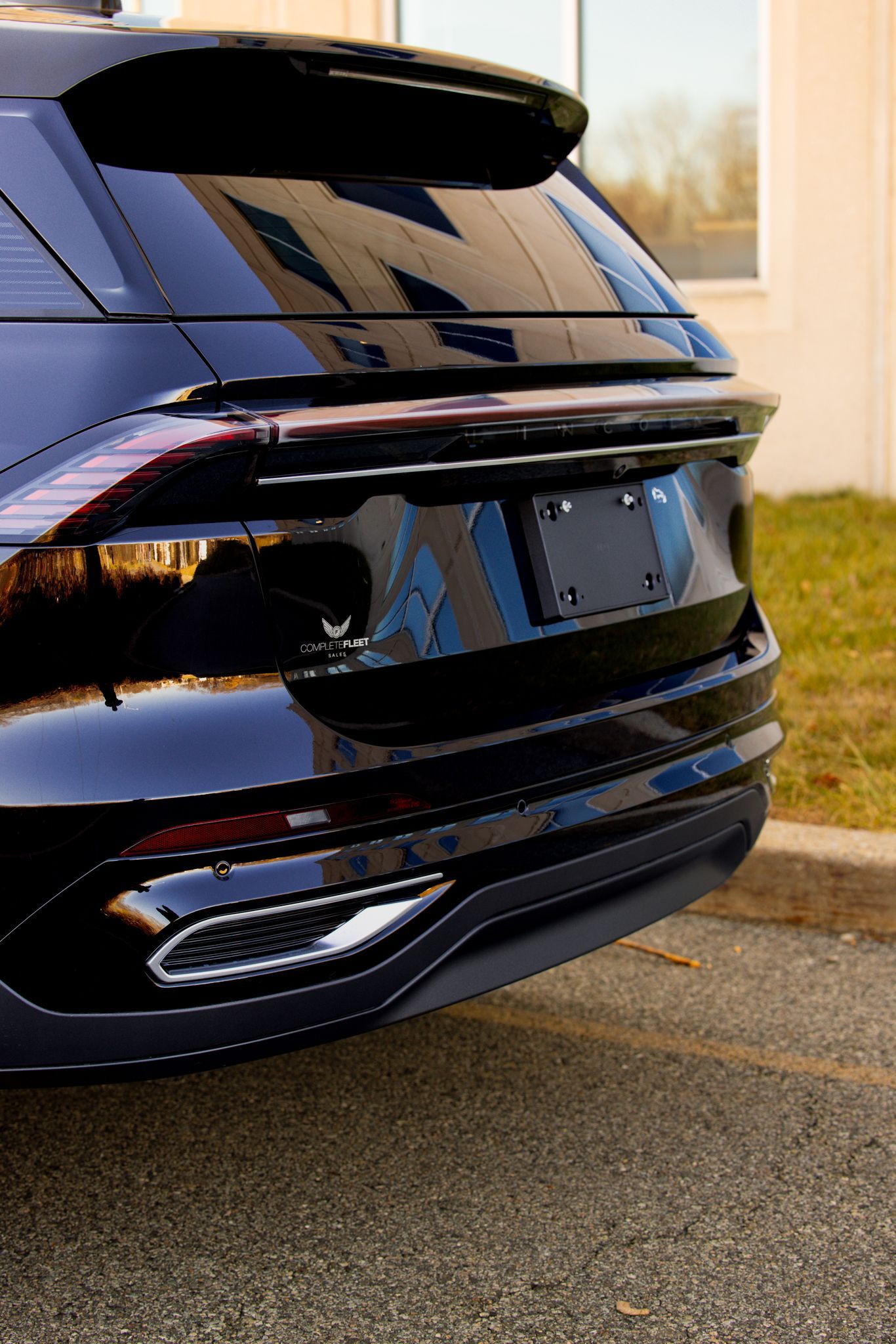 A black car is parked on the side of the road in front of a building.