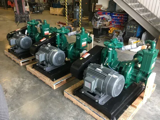 Green centrifugal pumps with electric motors staged on pallets in the Rhino Pumps shop