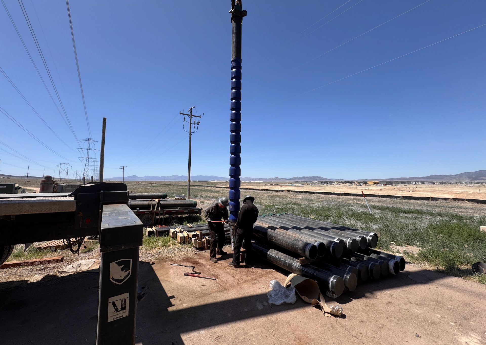 Crew setting a vertical pump column at a field site
