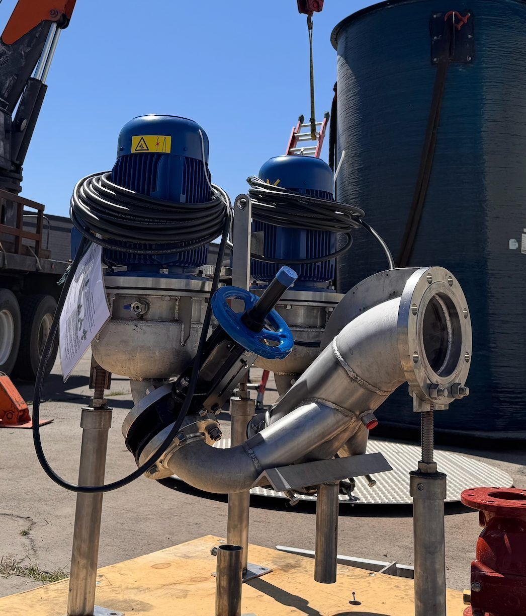 Two pumps with blue motors on angled piping at an outdoor wastewater pump station
