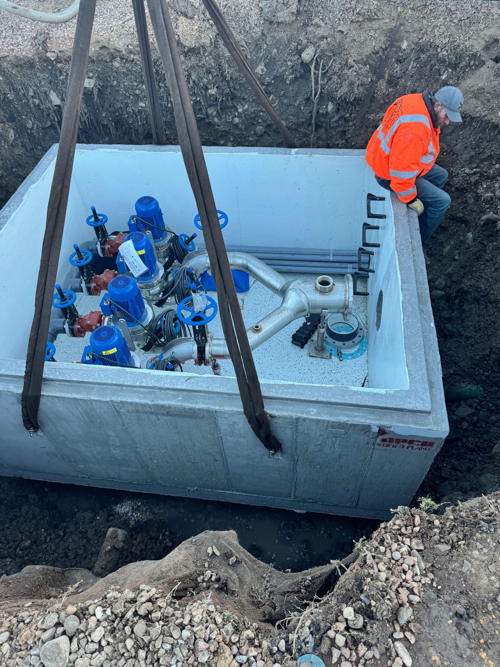 A man is working on a large concrete box in the dirt.
