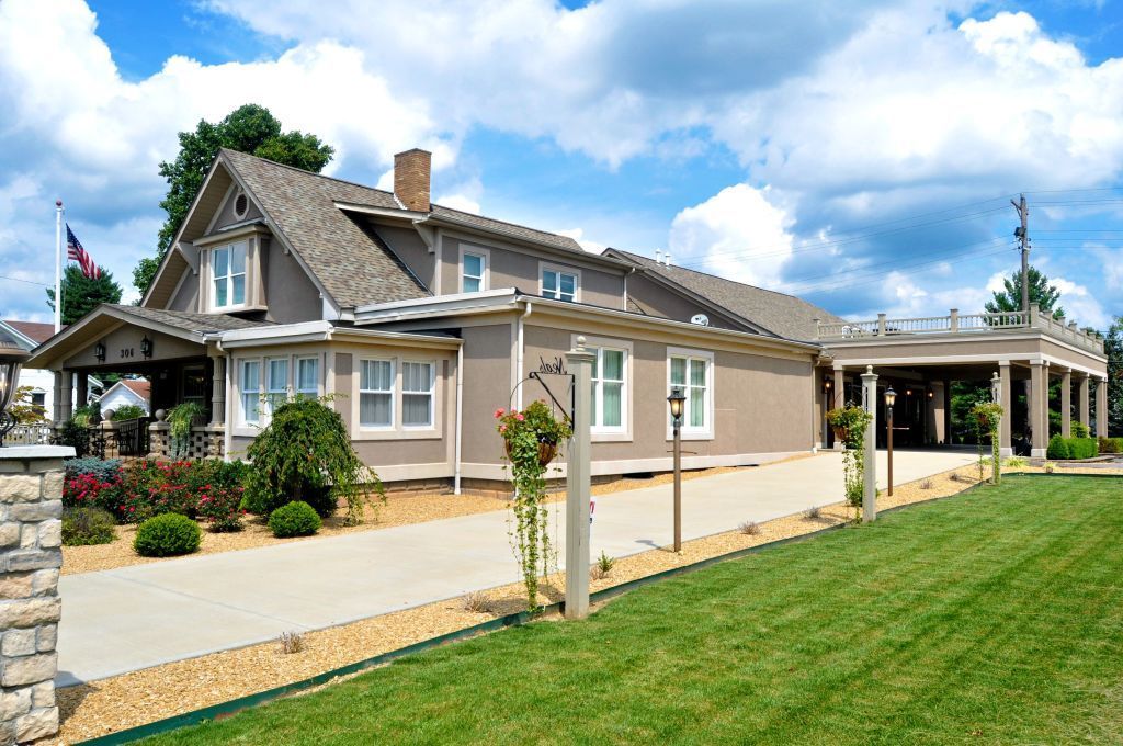 A large house with a lot of windows is sitting on top of a lush green lawn.