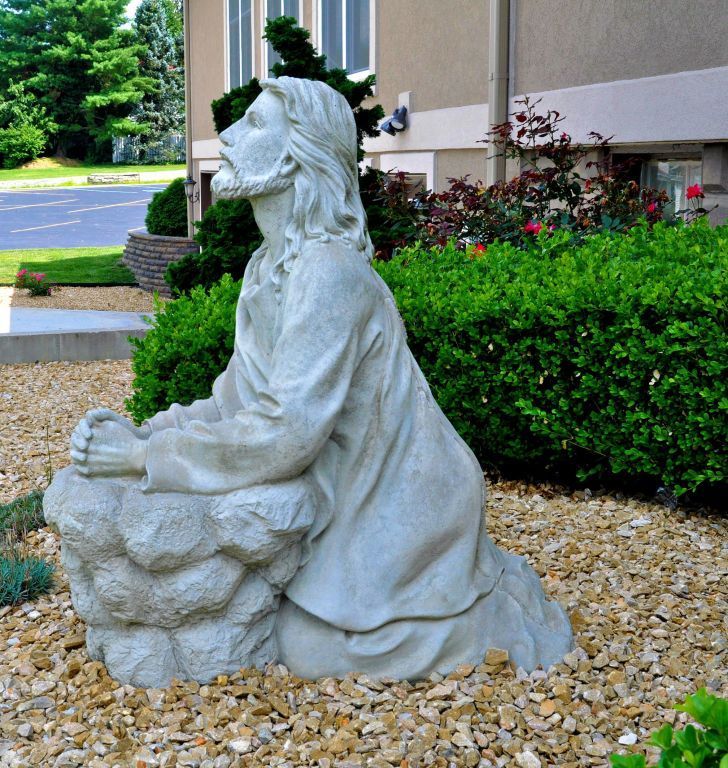 A statue of jesus is kneeling on a rock
