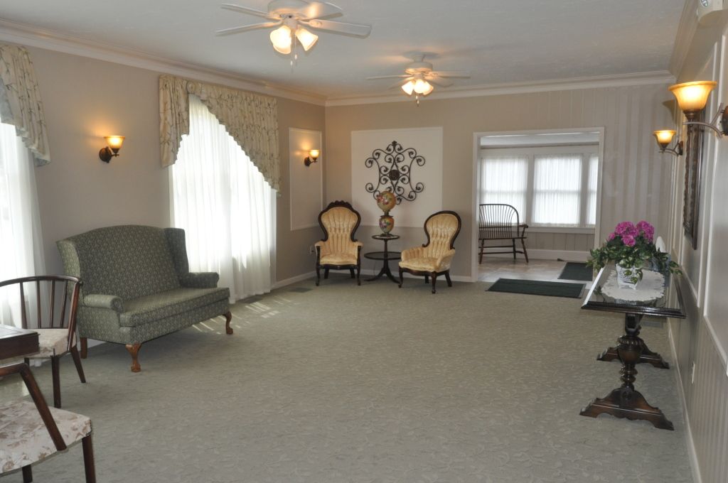 A living room with a couch , chairs , a table and a ceiling fan.