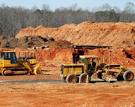 Un bulldozer et une niveleuse sont garés dans un champ de terre