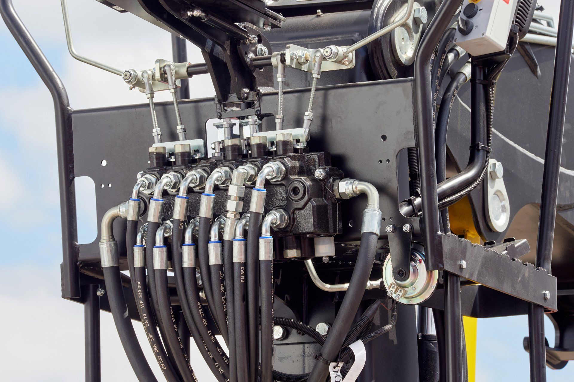 Gros plan sur les vannes de commande hydrauliques et les flexibles d'une machinerie lourde.