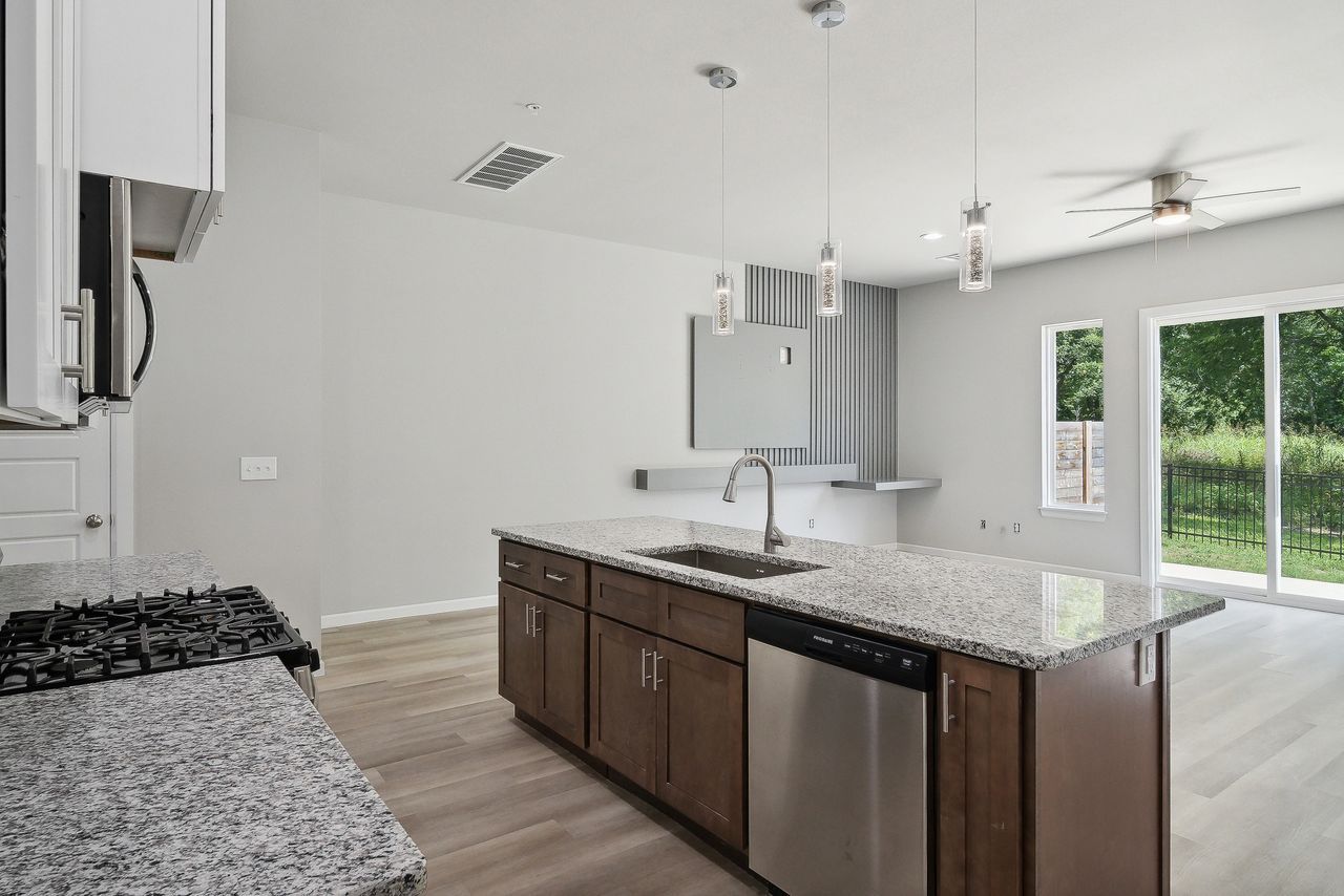 Kitchen with granite countertops, stainless steel appliances, and wooden cabinets. Sliding glass door to outdoors.