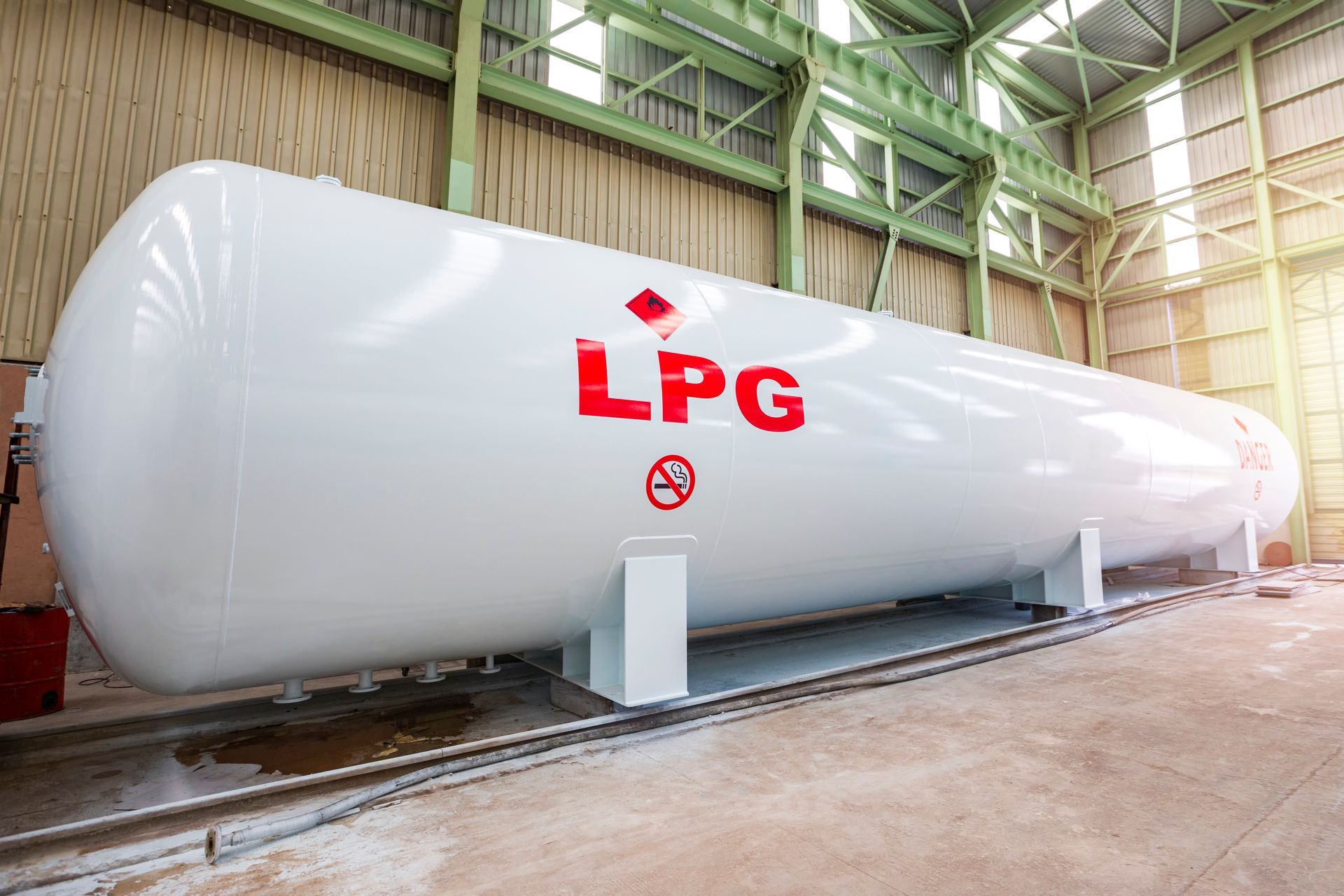 Gran tanque blanco de almacenamiento de GLP en un almacén industrial, con las letras rojas 