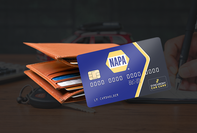 NAPA auto parts credit card next to a wallet, with a person writing in the background. | Integrity Auto Repair