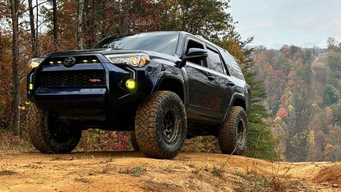 A black toyota 4runner is parked on top of a dirt hill.