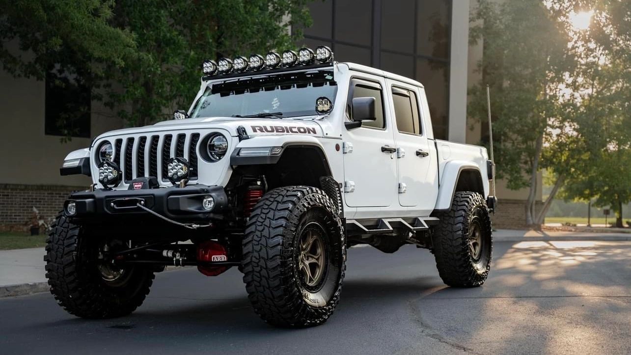 A white jeep is parked on the side of the road in front of a building.