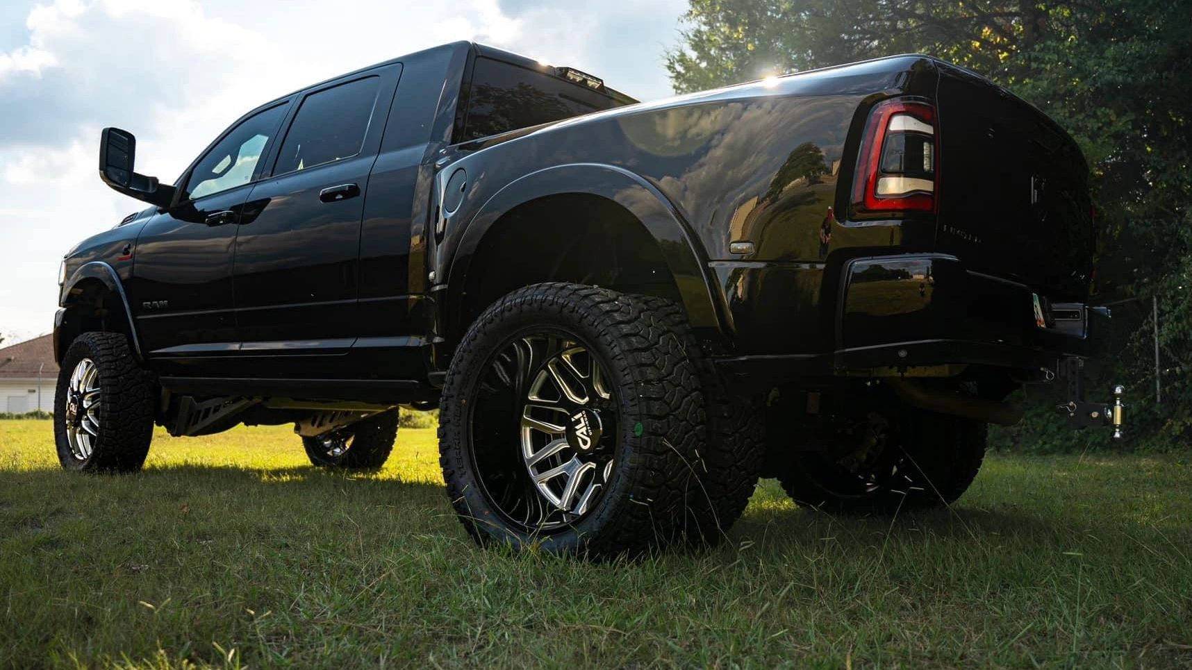 A black truck is parked in a grassy field.