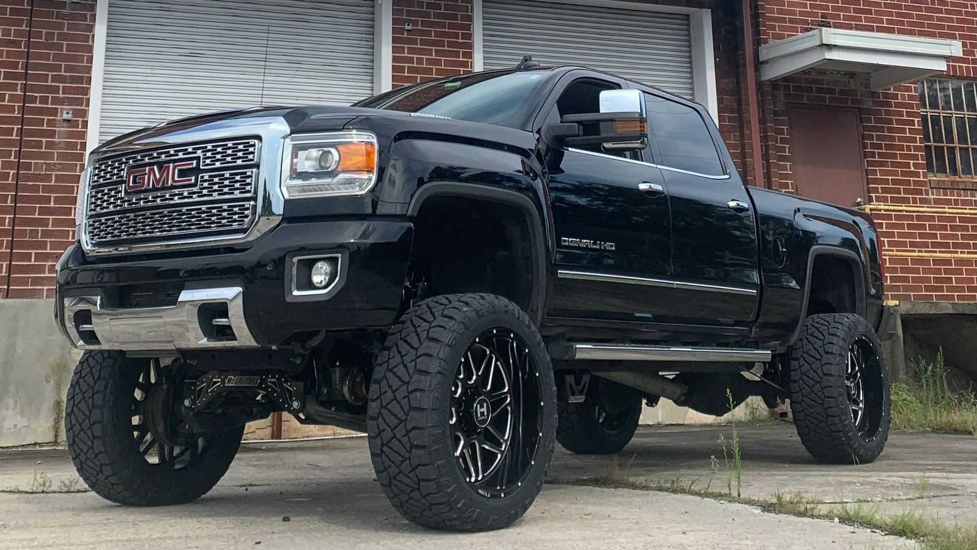 A black truck is parked in front of a brick building.