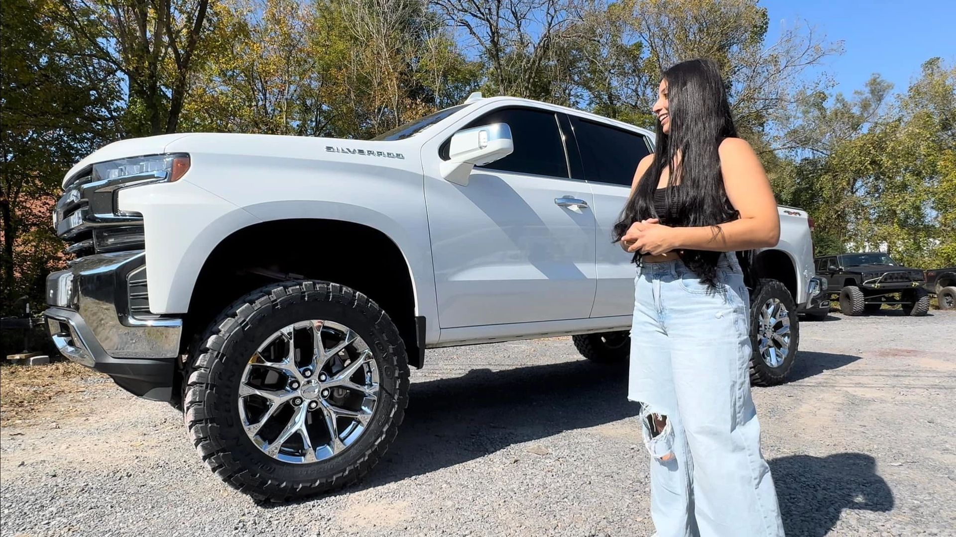A woman is standing in front of a white truck.