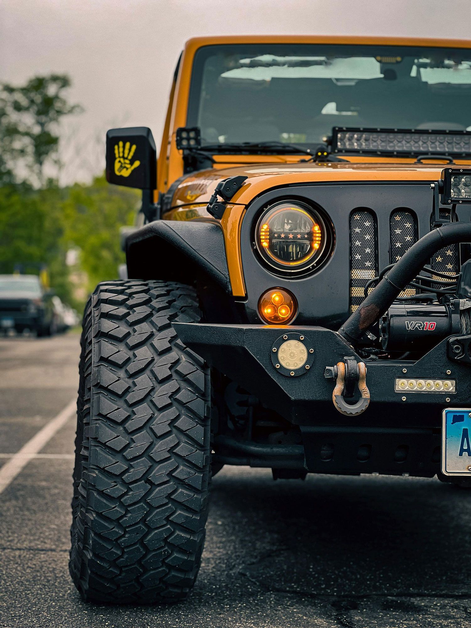A yellow jeep is parked in a parking lot.