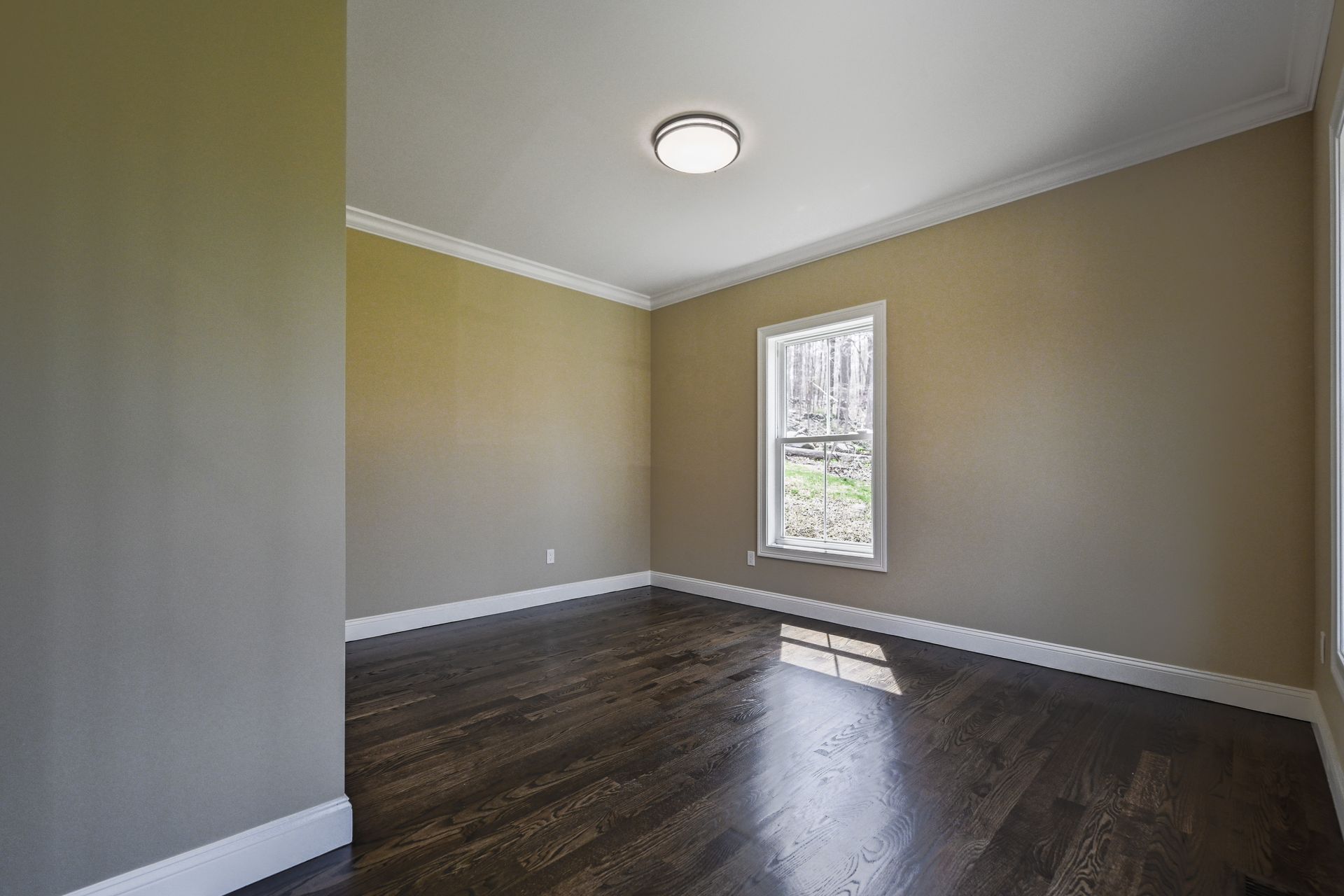 An empty room with hardwood floors and a window.