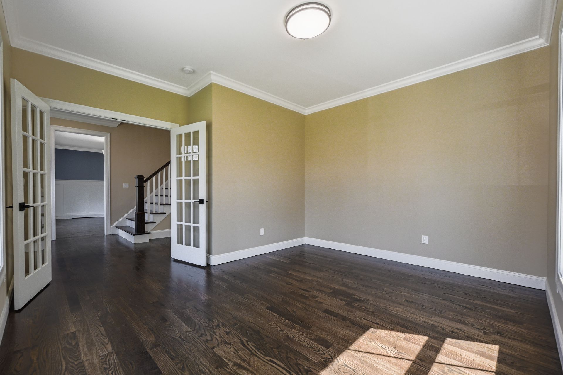 An empty living room with hardwood floors and a staircase.