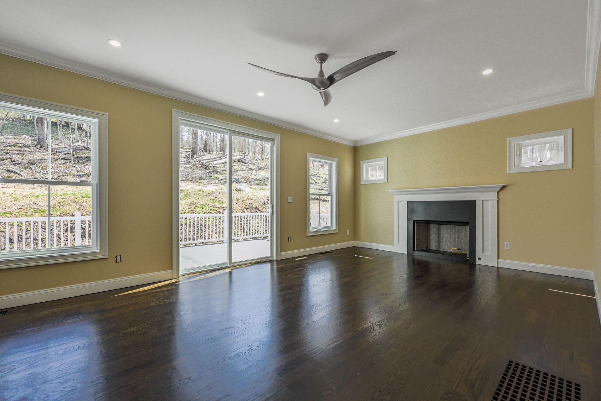 An empty living room with a fireplace and a ceiling fan.