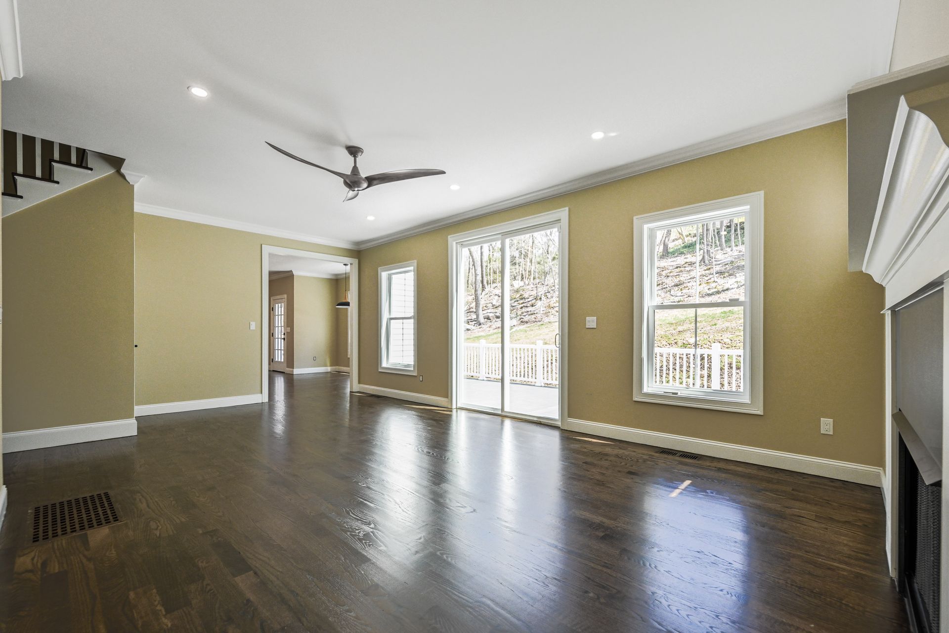 An empty living room with hardwood floors and a ceiling fan.