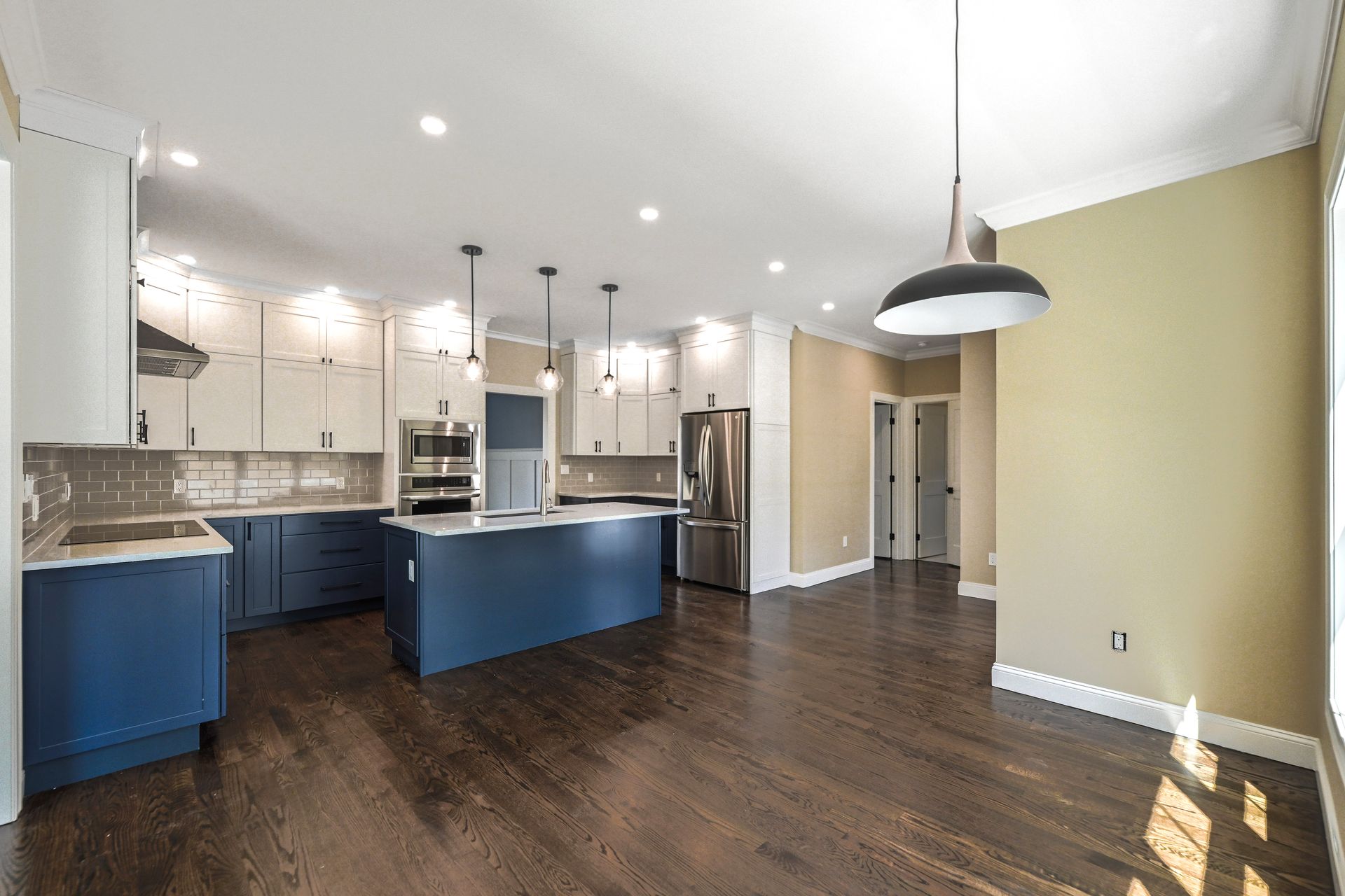 An empty kitchen with blue cabinets and stainless steel appliances.
