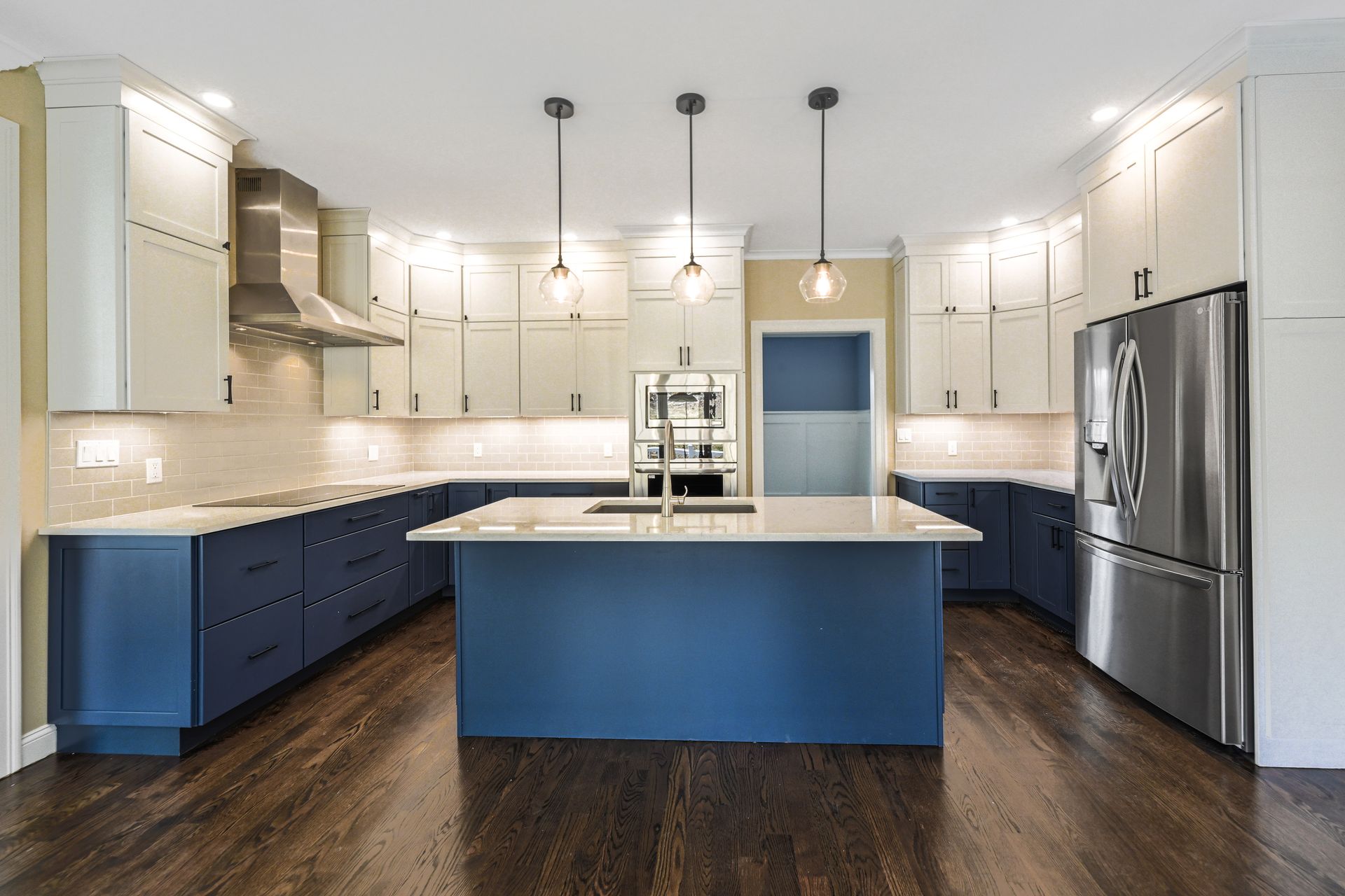 A kitchen with blue and white cabinets and stainless steel appliances.
