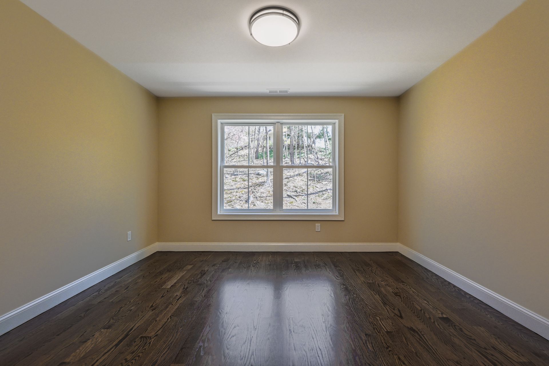 An empty room with hardwood floors and two windows