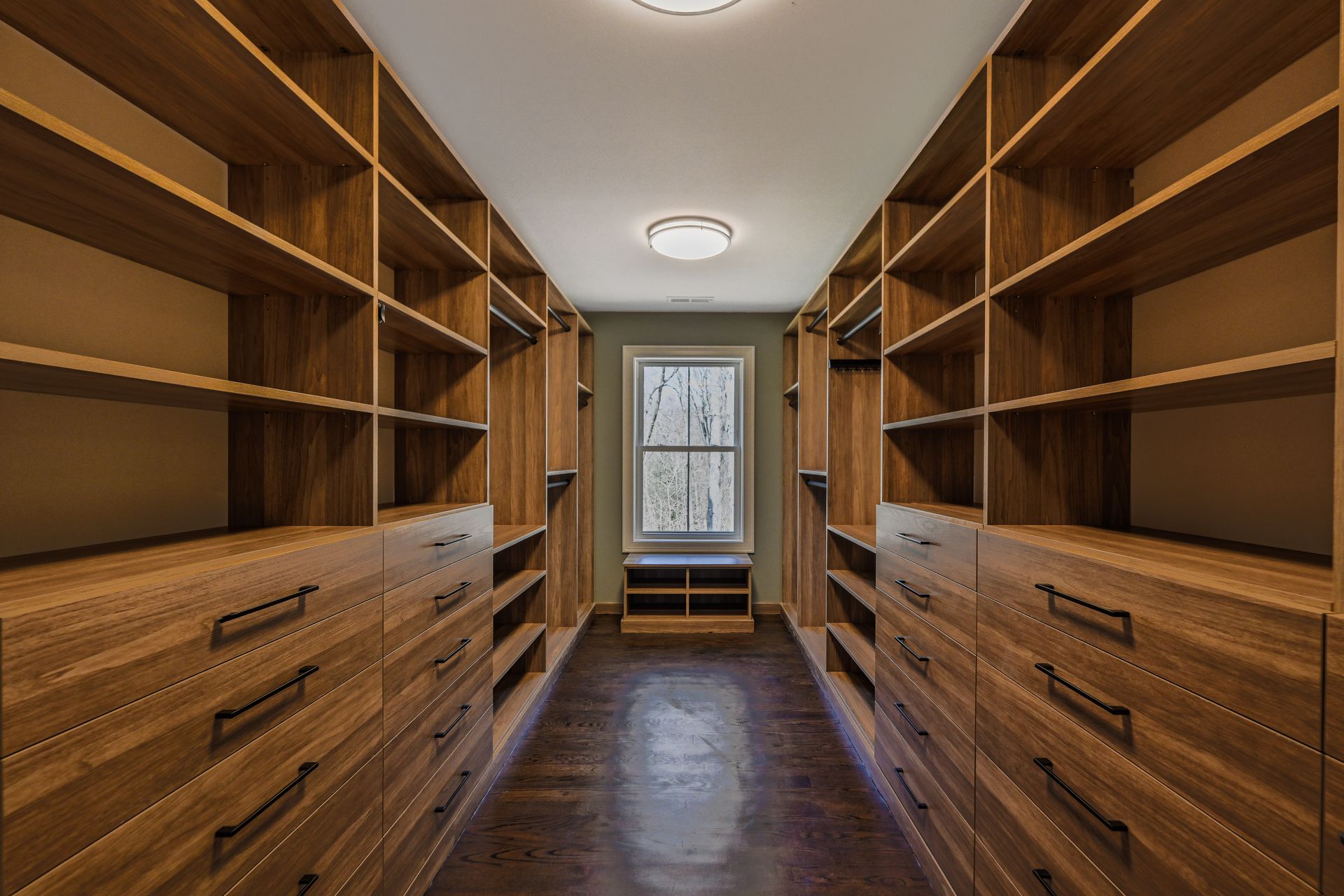 A walk in closet with lots of wooden shelves and drawers.