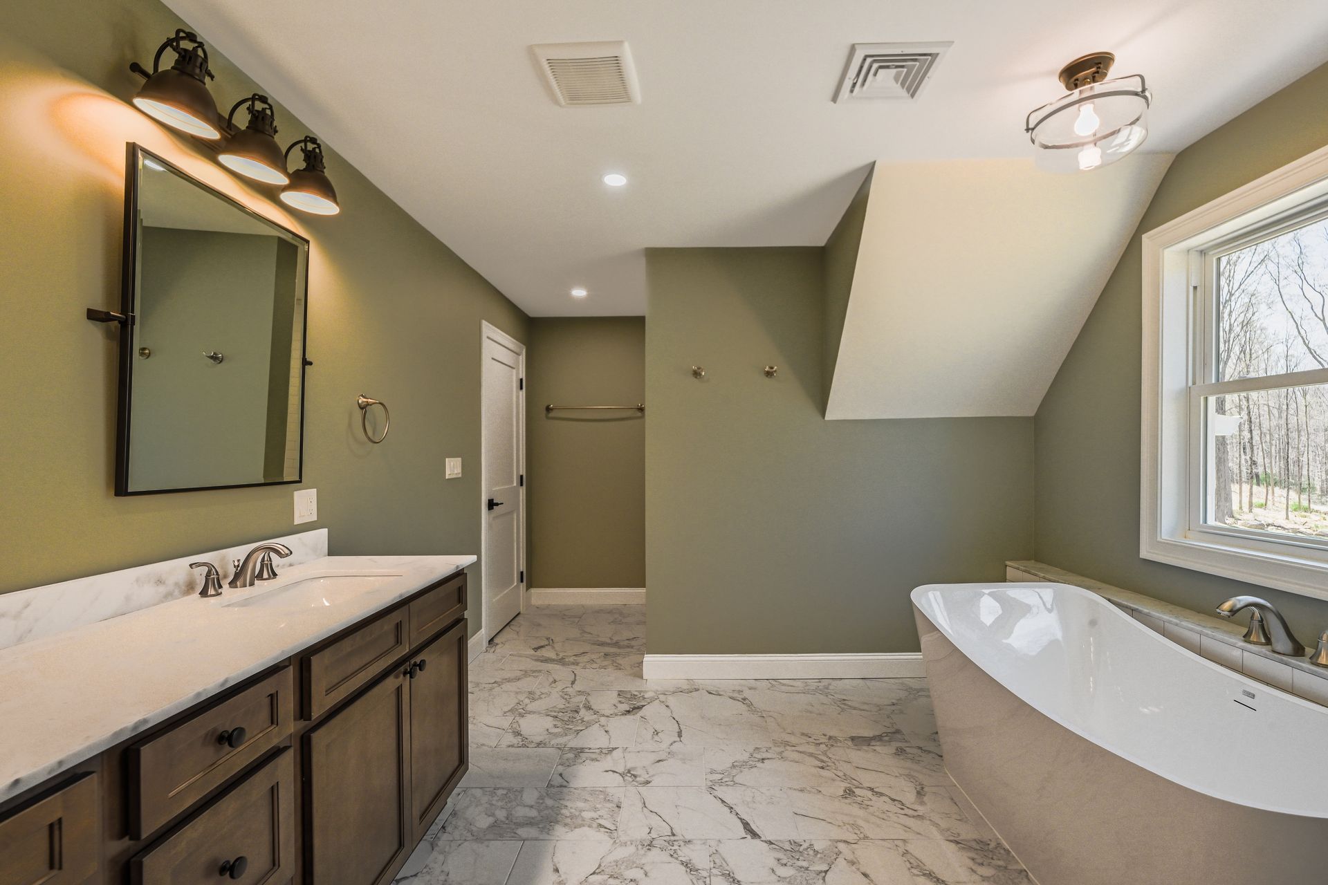 A bathroom with a tub , sink , mirror and window