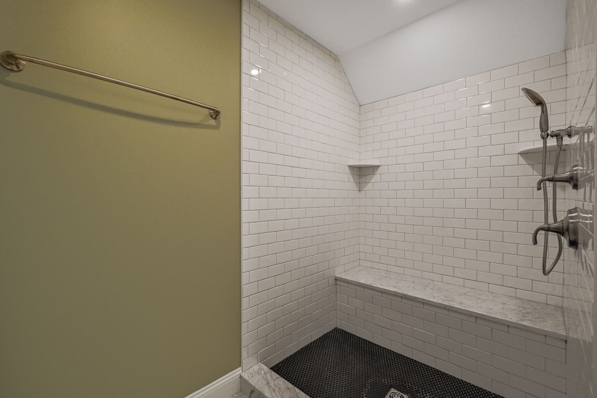 A bathroom with white tiles and a walk in shower.