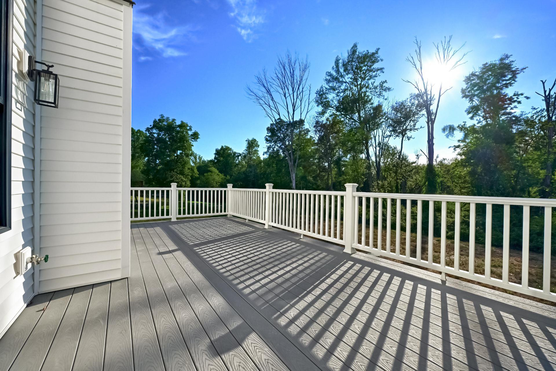 A deck with a white railing and trees in the background