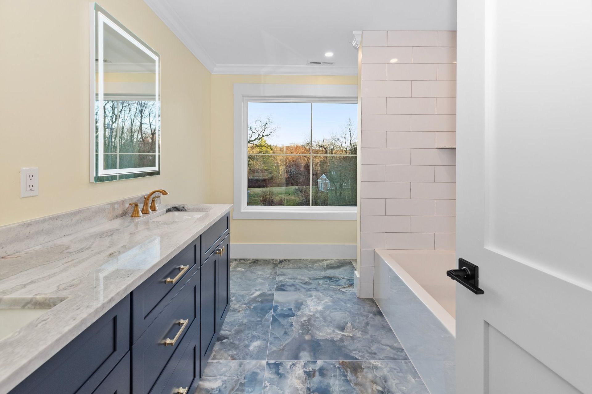 A bathroom with two sinks a mirror and a tub
