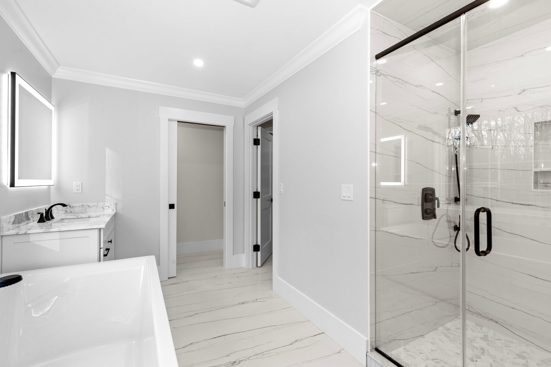 A bathroom with a tub , sink , shower and mirror.