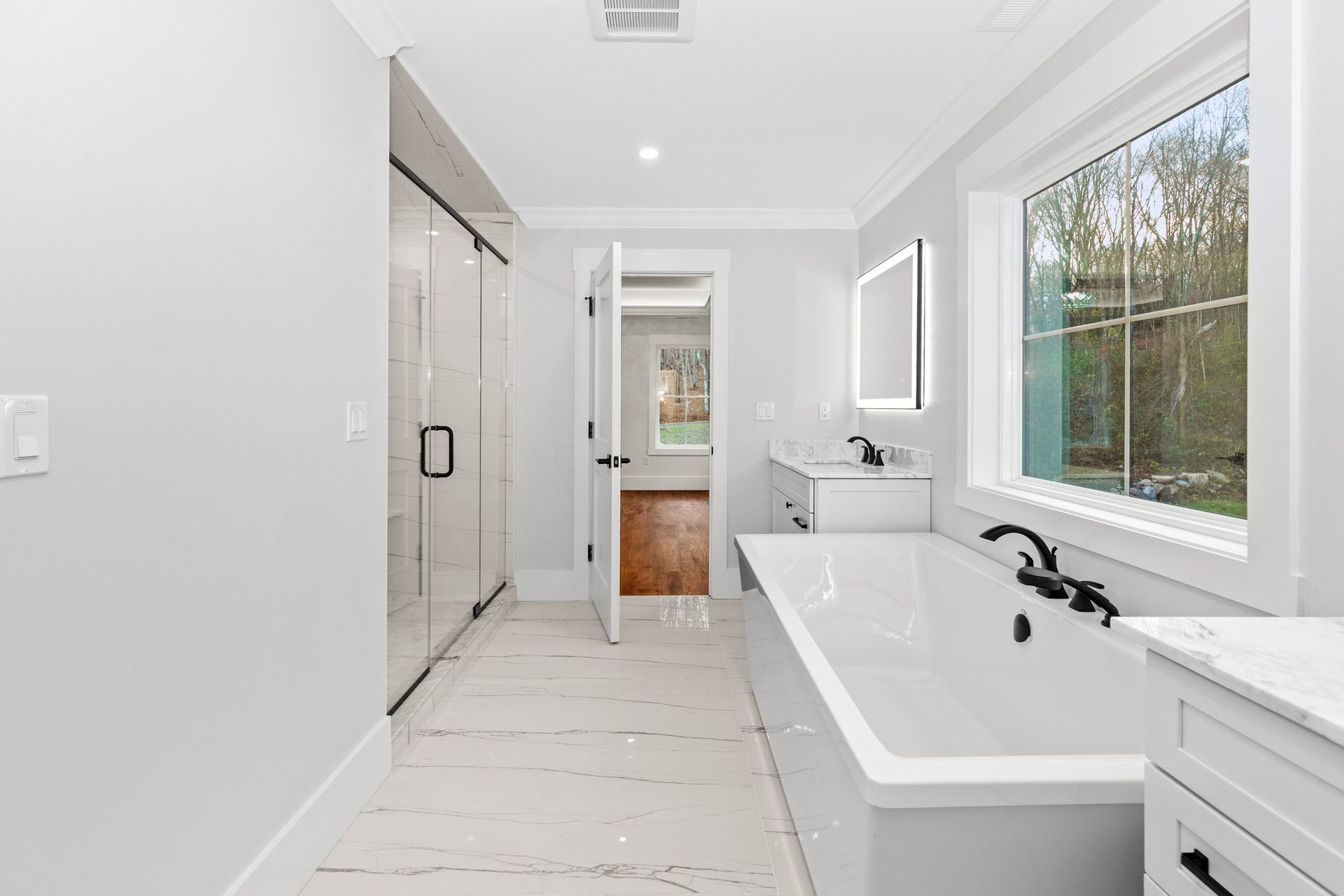 A bathroom with a tub , sink , mirror and window
