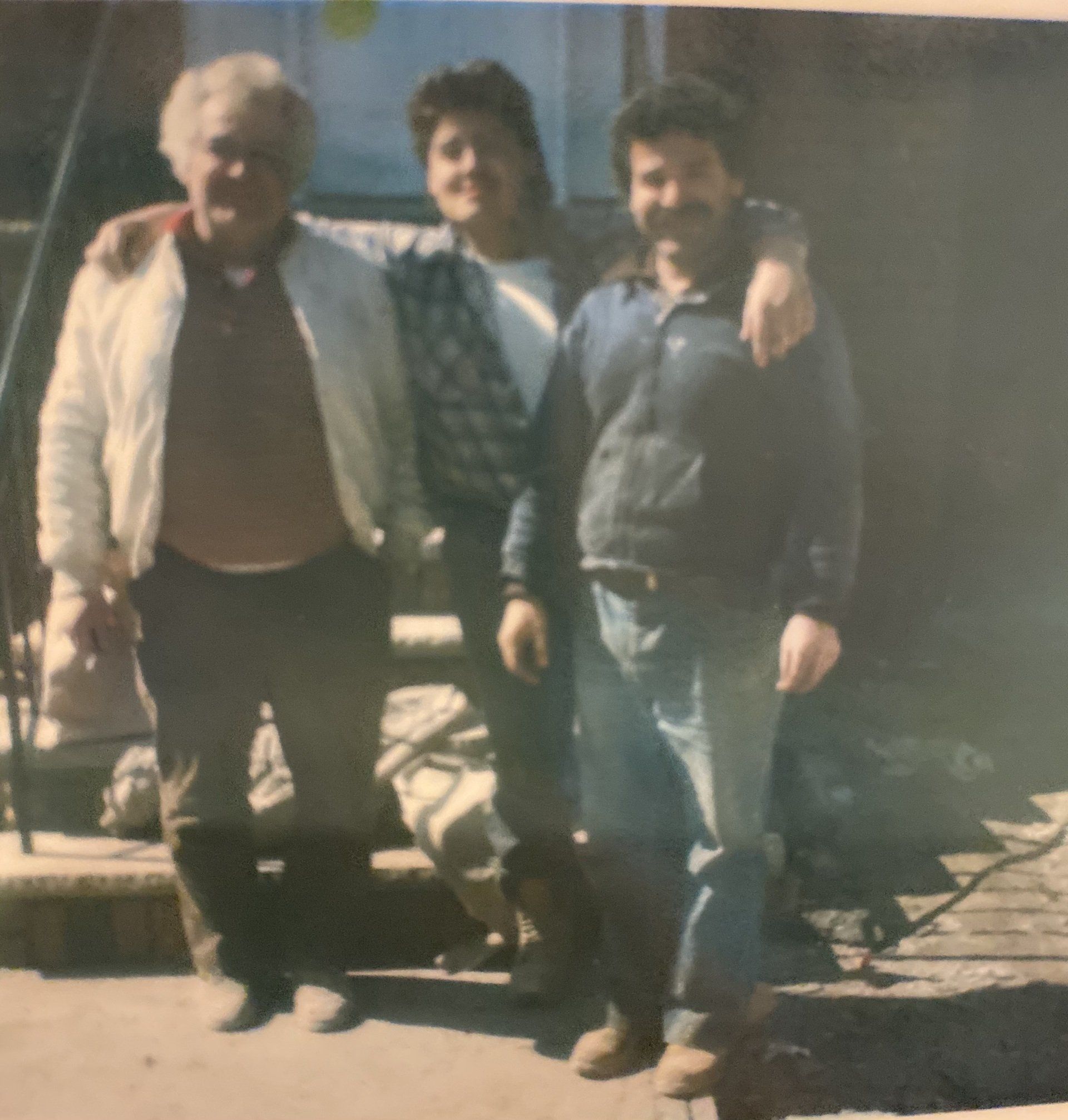 Three men are posing for a picture and one has his arm around the other 's shoulder
