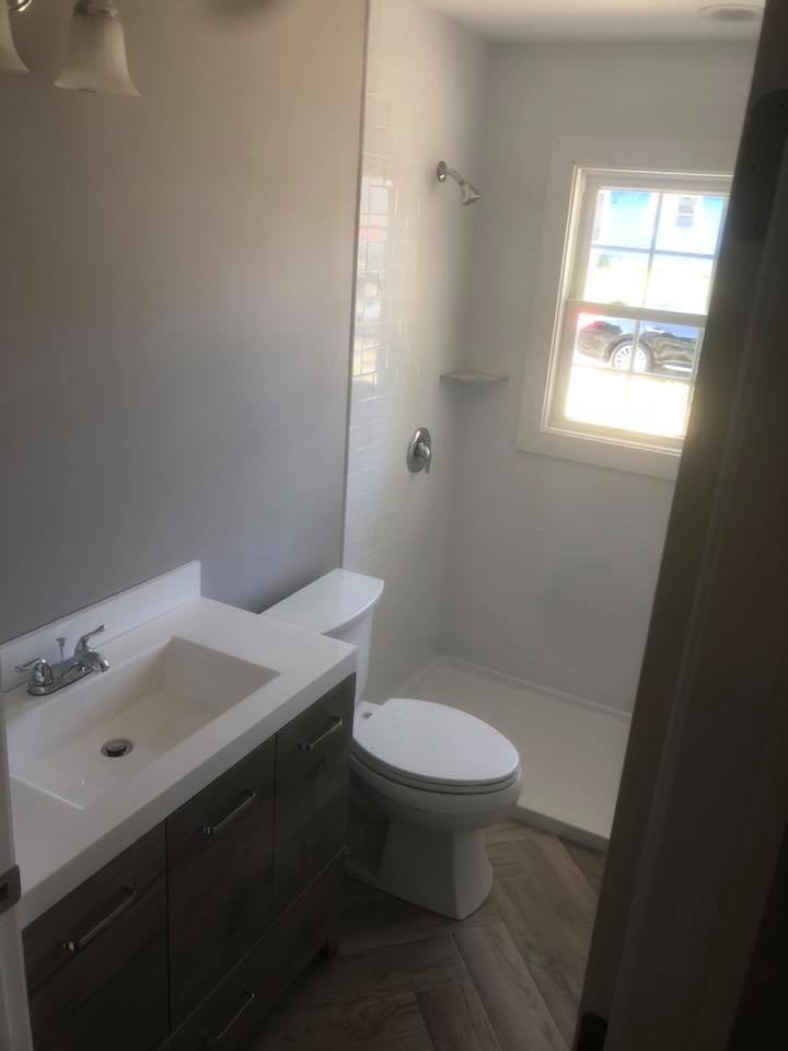 A bathroom with a toilet , sink and shower.