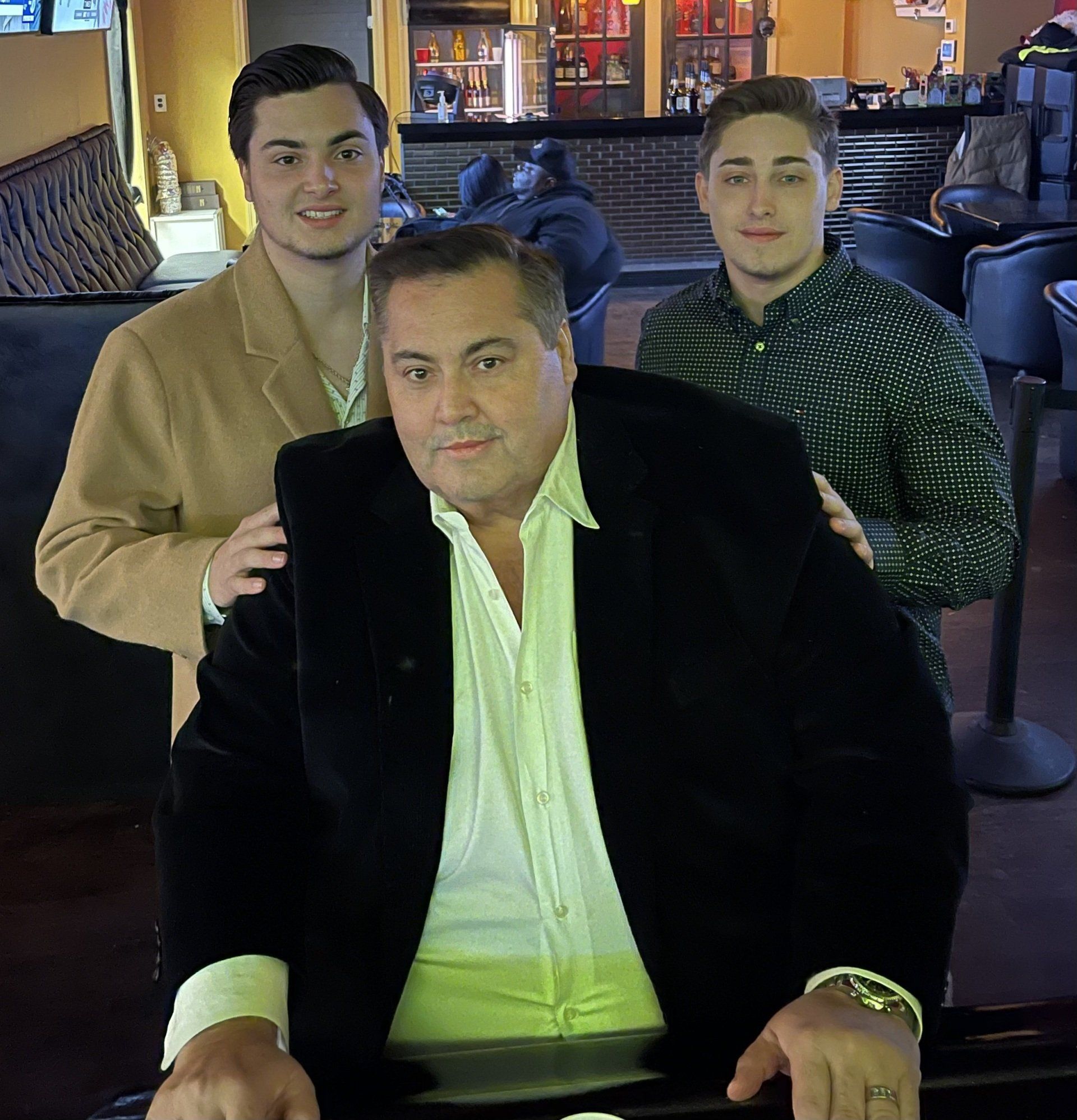 A man in a black jacket is surrounded by his two sons
