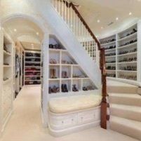 A walk in closet with stairs and shelves filled with shoes.