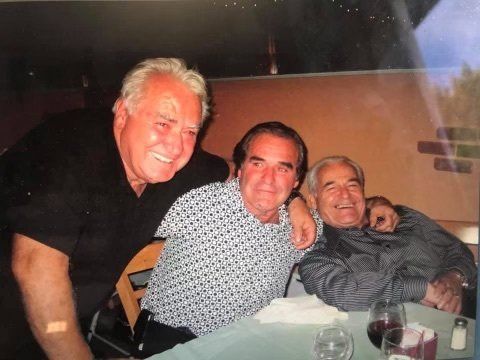 Three men are posing for a picture while sitting at a table