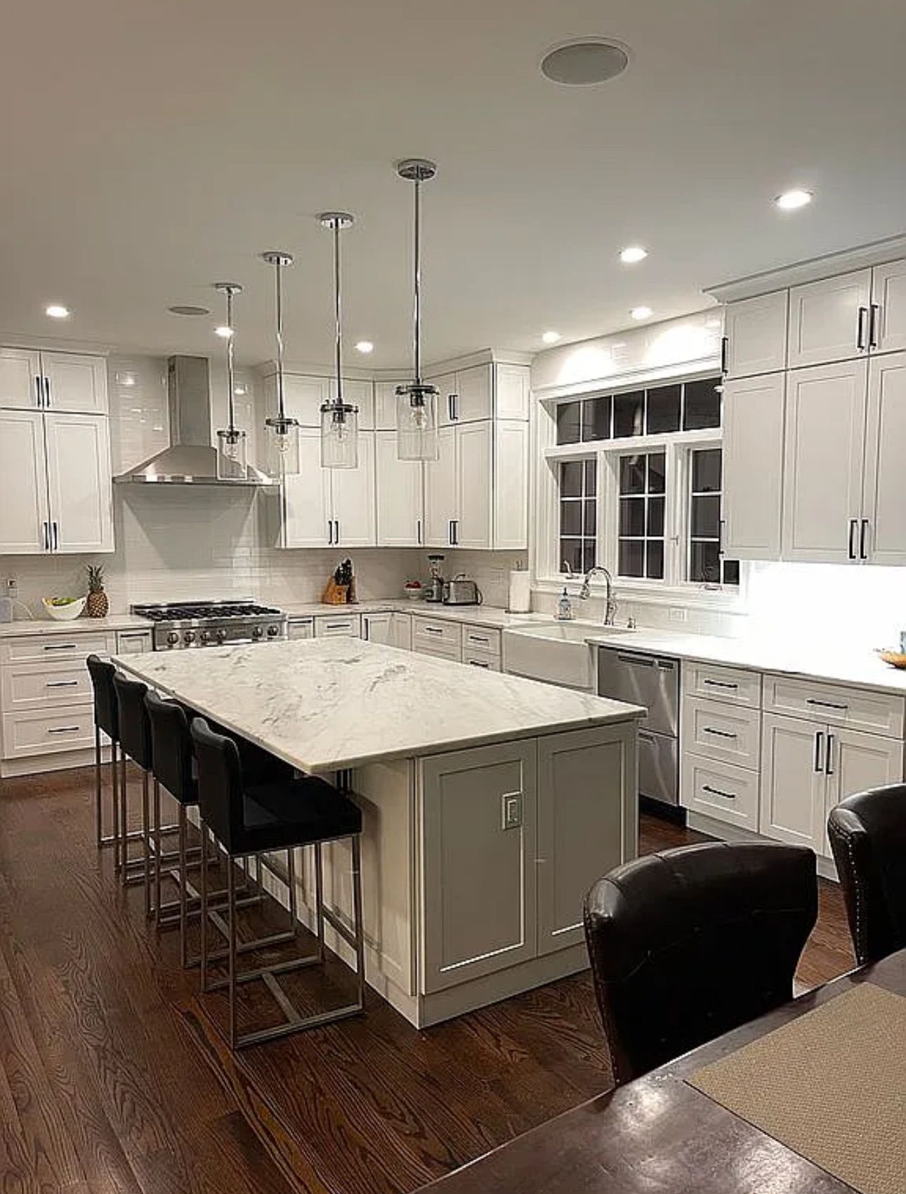 A kitchen with white cabinets and a large island in the middle.