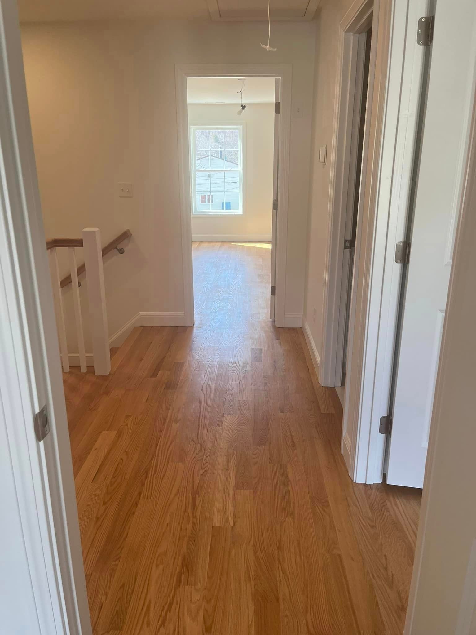 A hallway with hardwood floors and white walls in a house.