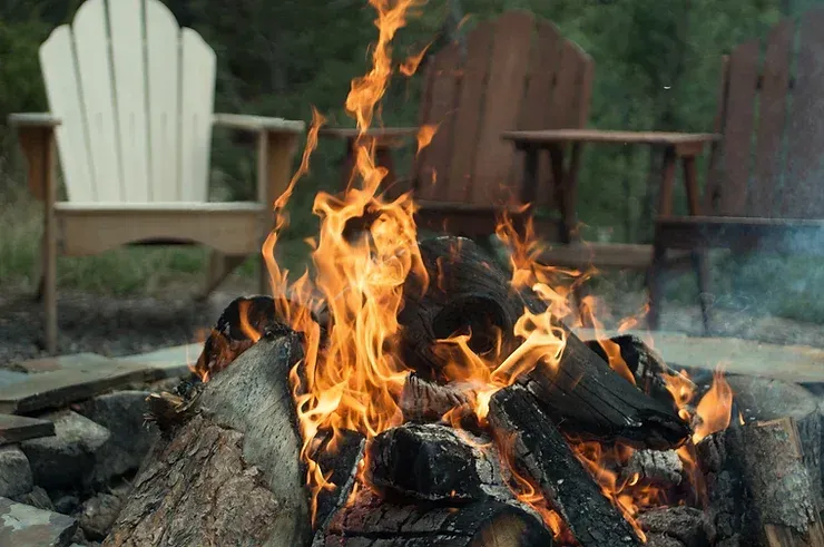 A fire pit with two chairs in the background.