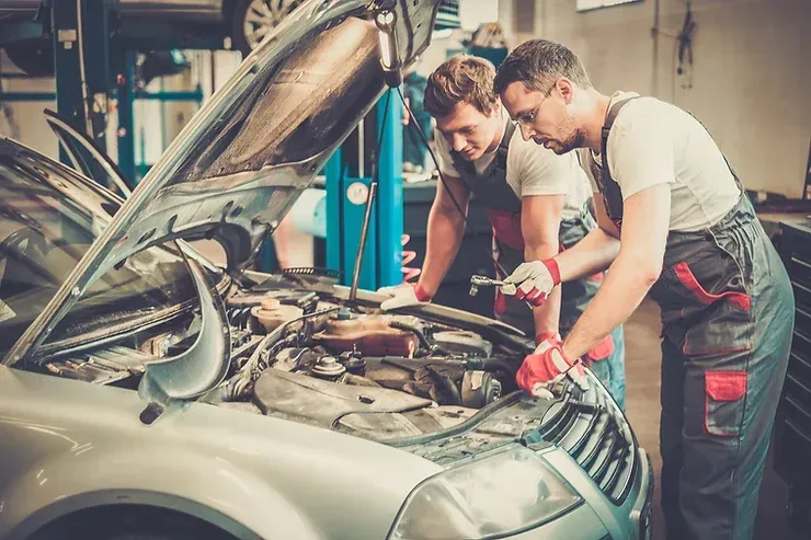 Two mechanics are working on a car in a garage.