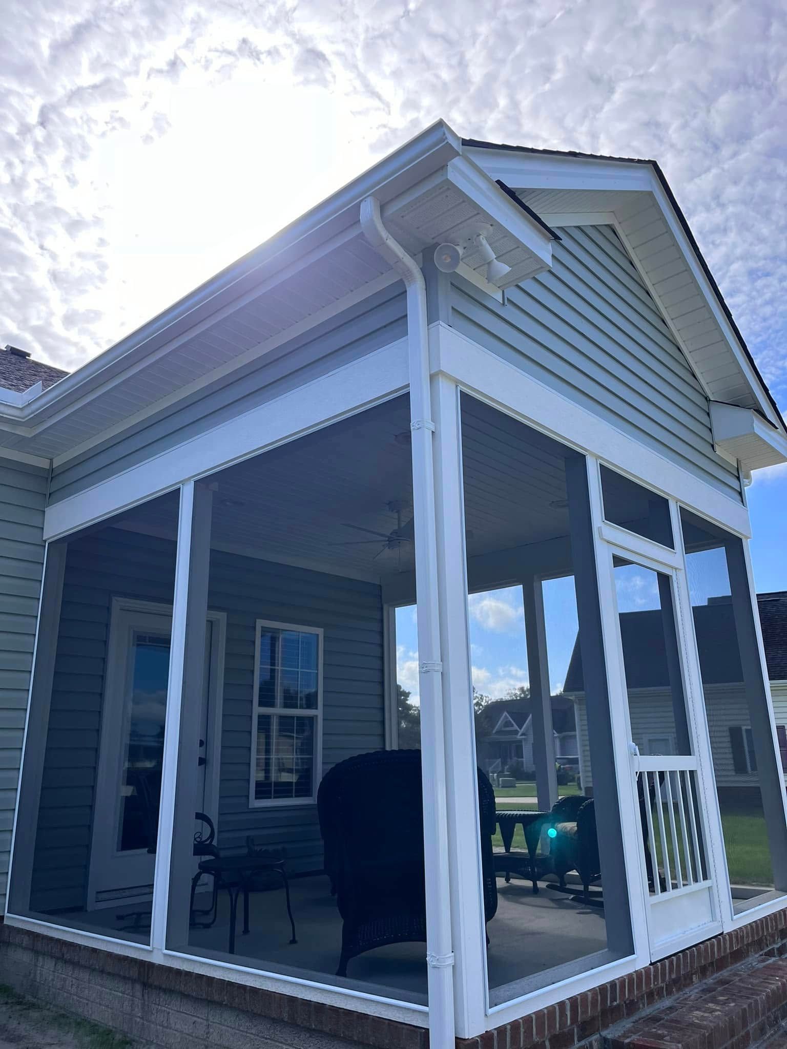 A screened in porch on the side of a house.