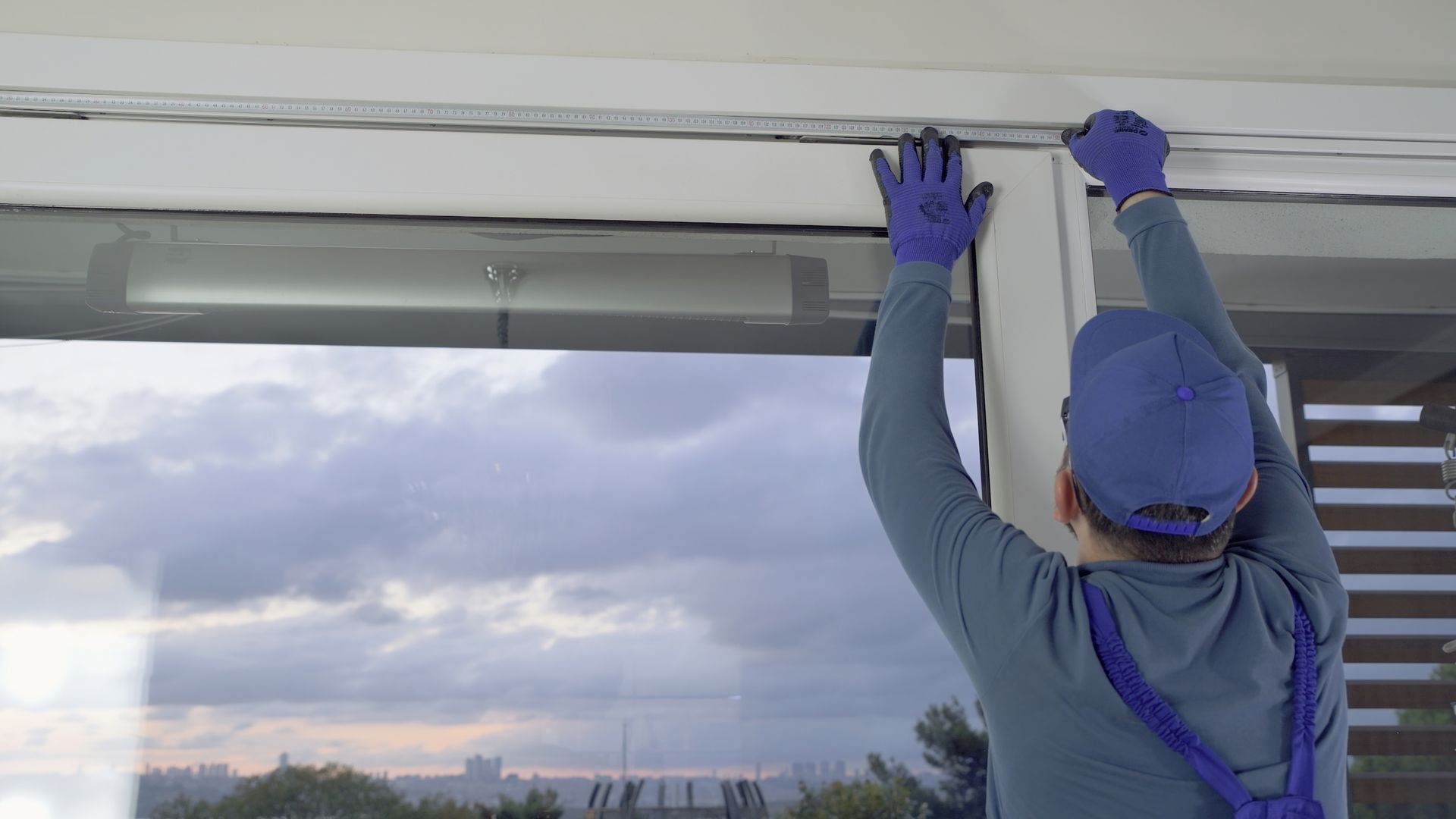 A man is installing blinds on a window.